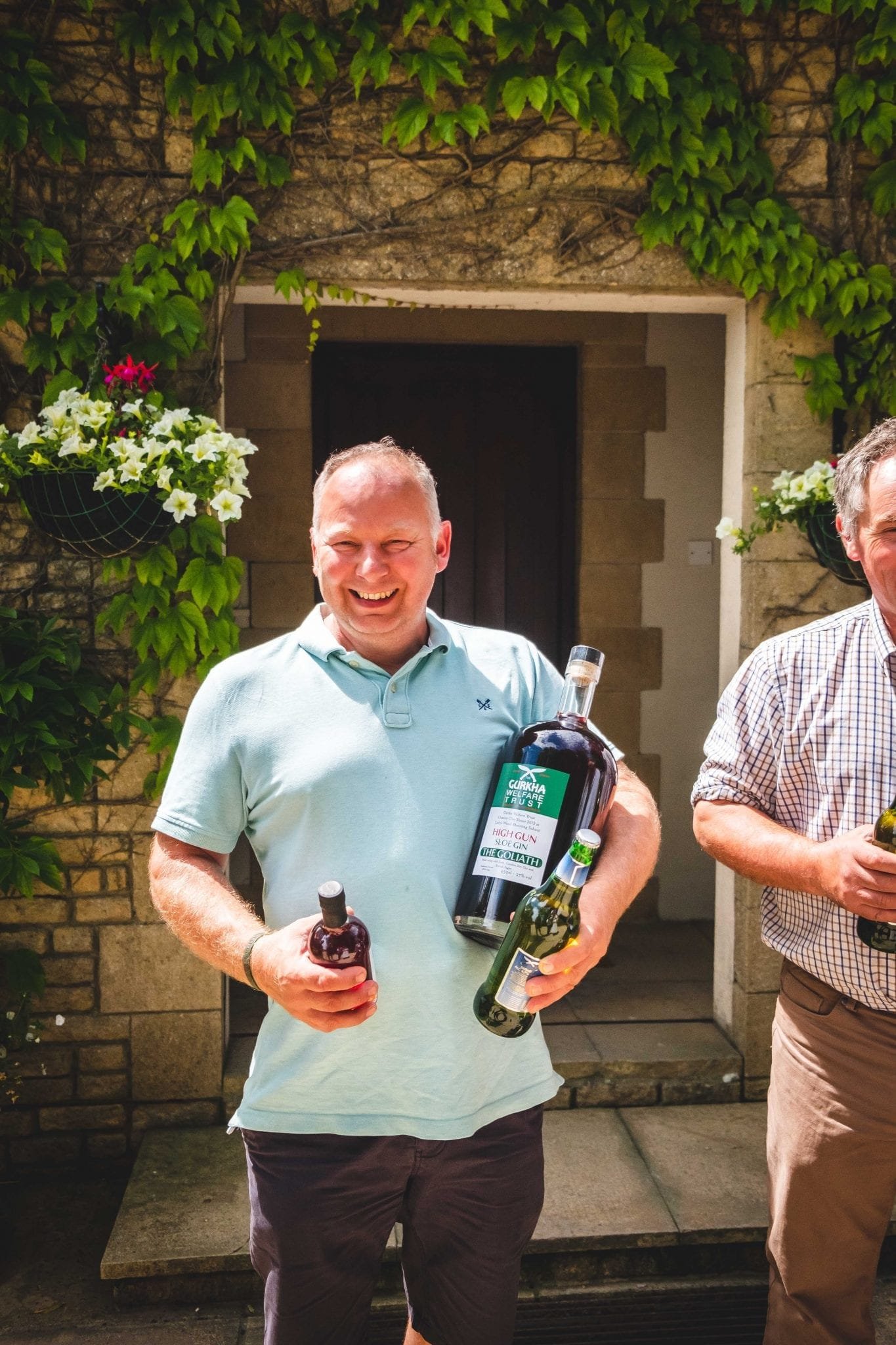 The individual winner from the Gurkha Welfare Trust Charity Shoot at Lady's Wood Shooting School holds his prize of a giant bottle of sloe gin